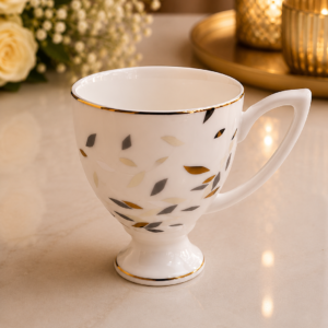 White ceramic mug set with modern leaf pattern, gold rim, and elegant pedestal base.